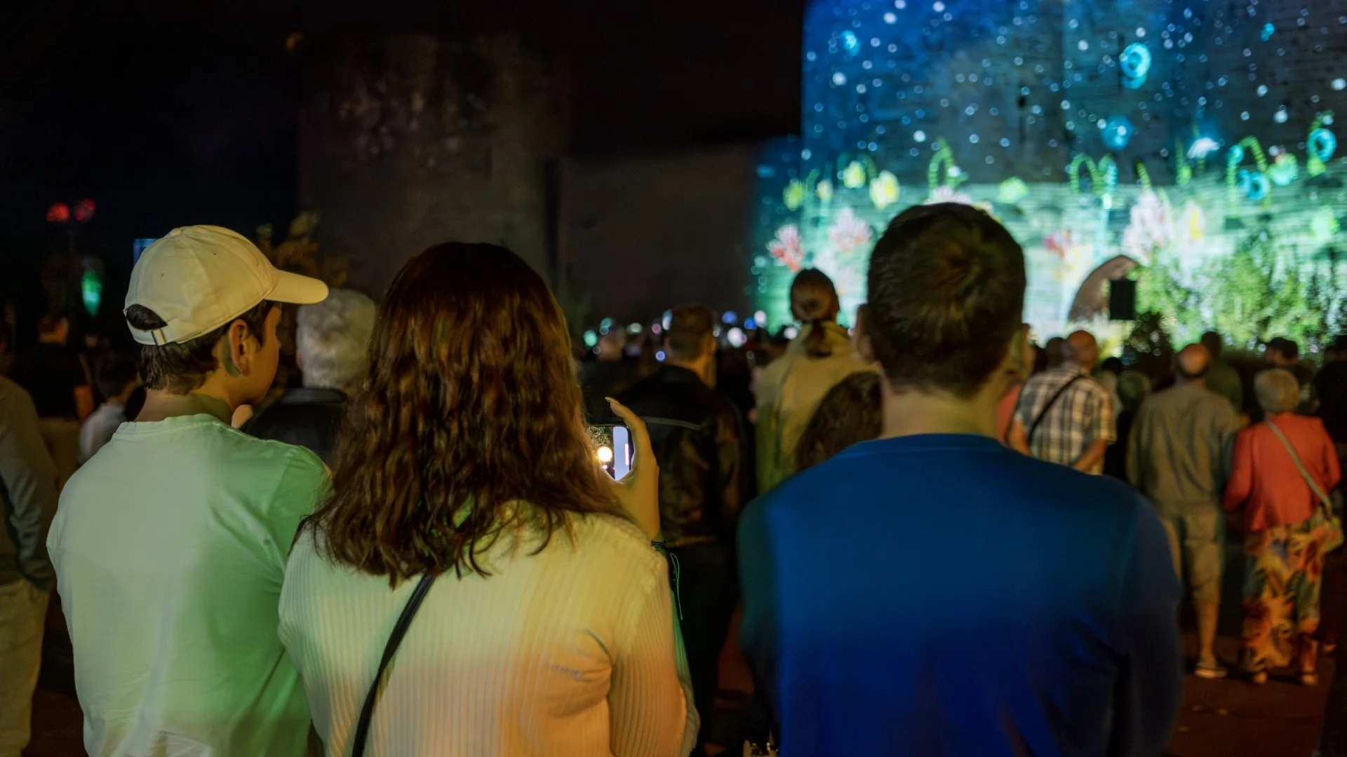 Photo prise lors du mapping, on peux y voir une famille devant le mapping. Une des personnes le film avec son téléphone